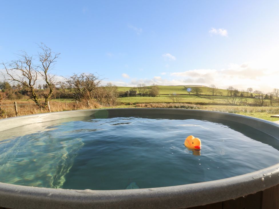 A hot tub with a rubber duck in the water and hills in the background at Harriet in Llangurig