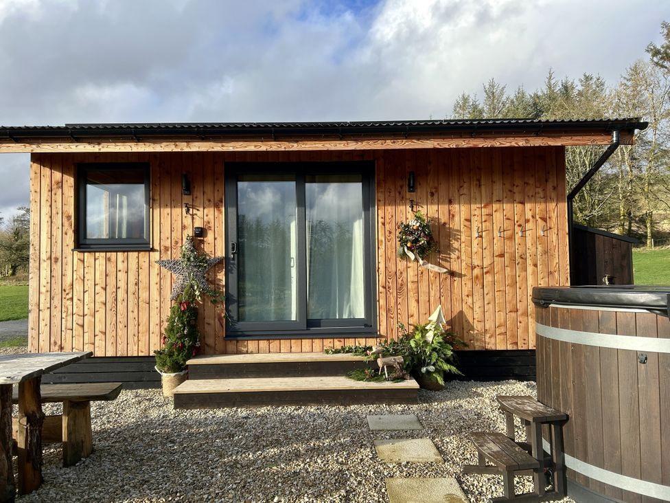 A wooden cabin with a hot tub and seating area at Harriet in Llangurig