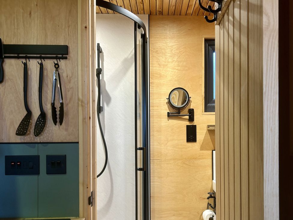 A bathroom with a shower and hooks on the wall at Harriet in Llangurig