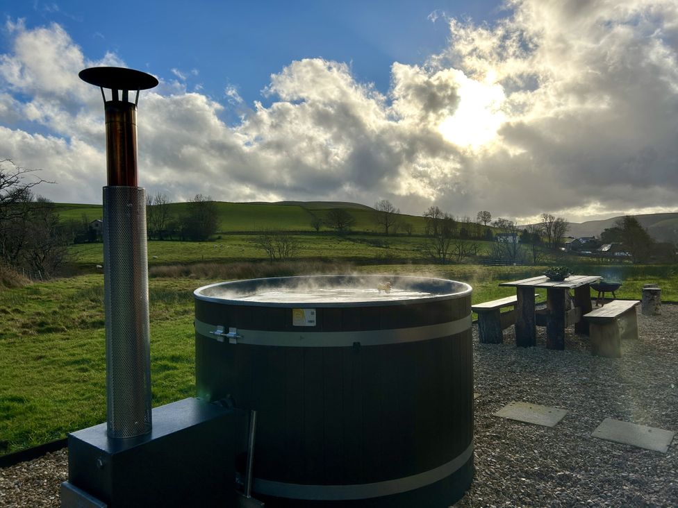 A hot tub with a chimney and wooden seating area at Harriet in Llangurig