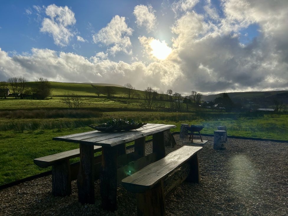 An outdoor area with wooden table and benches at Harriet in Llangurig