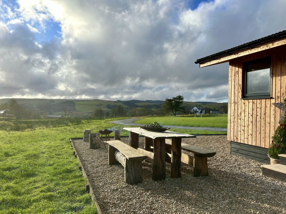 An outdoor area with a table and benches at Harriet in Llangurig