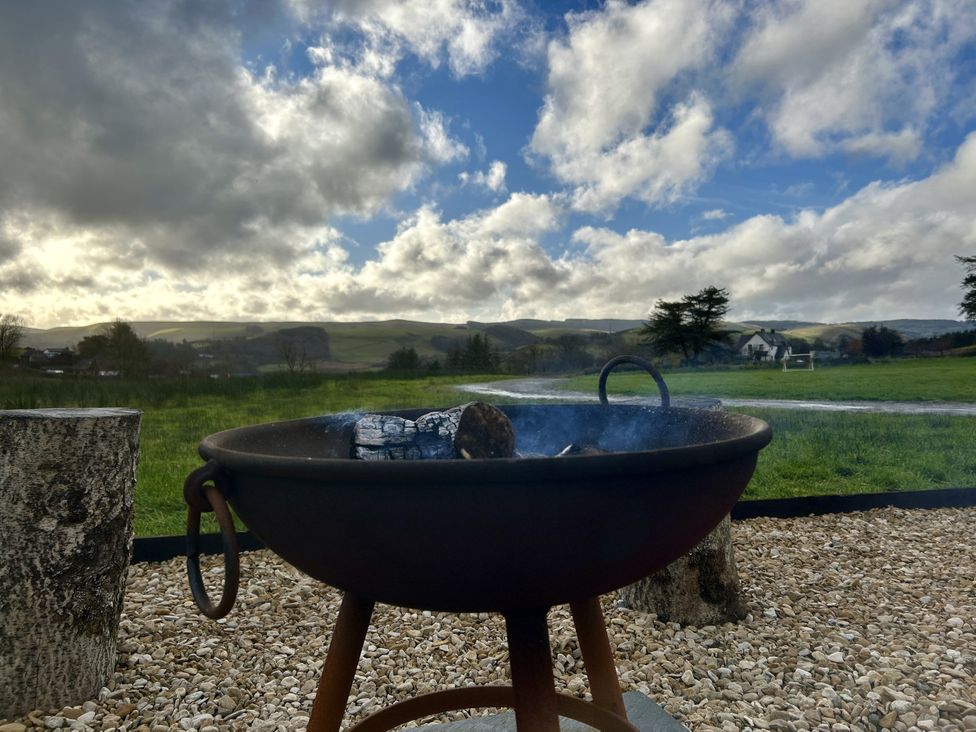 A fire pit with stones in a grassy area at Harriet in Llangurig