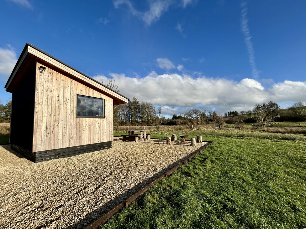 A wooden cabin beside a gravel area with a table at Harriet in Llangurig