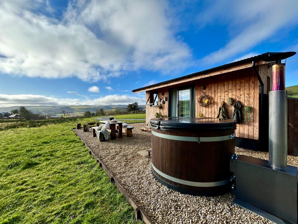 An outdoor area with a hot tub and wooden seating at Harriet in Llangurig