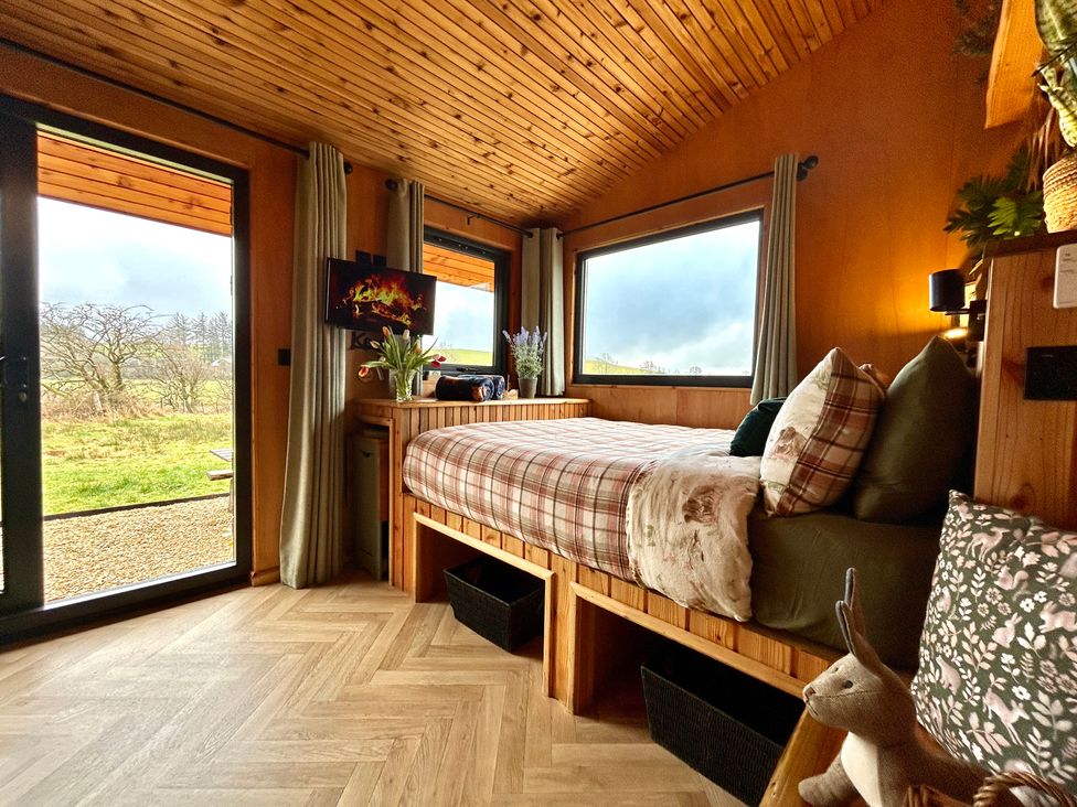 A bedroom with a bed and windows overlooking a garden at Harriet in Llangurig