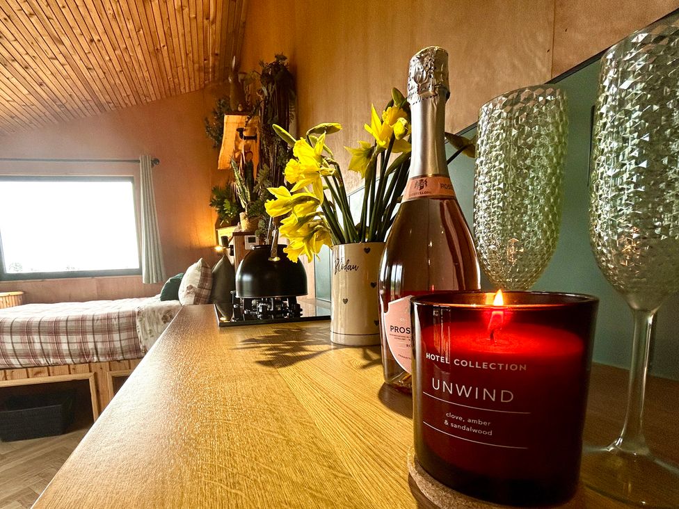 A bedroom with a bed, a window, and a table with a bottle and candle at Harriet in Llangurig