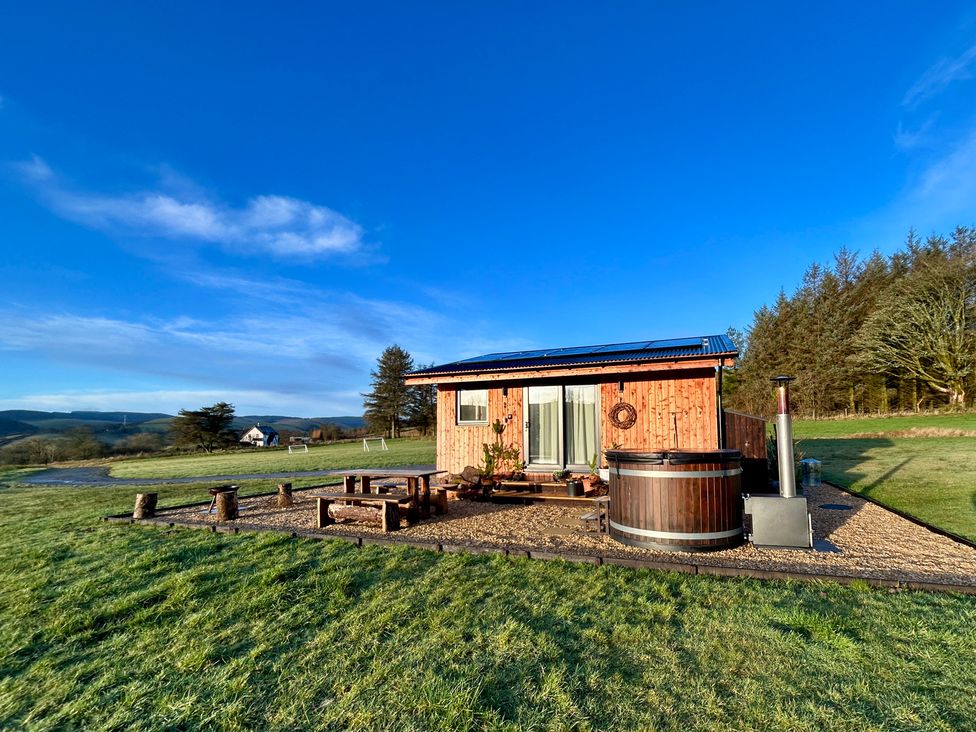 A cabin with a hot tub and wooden seating area at Harriet in Llangurig