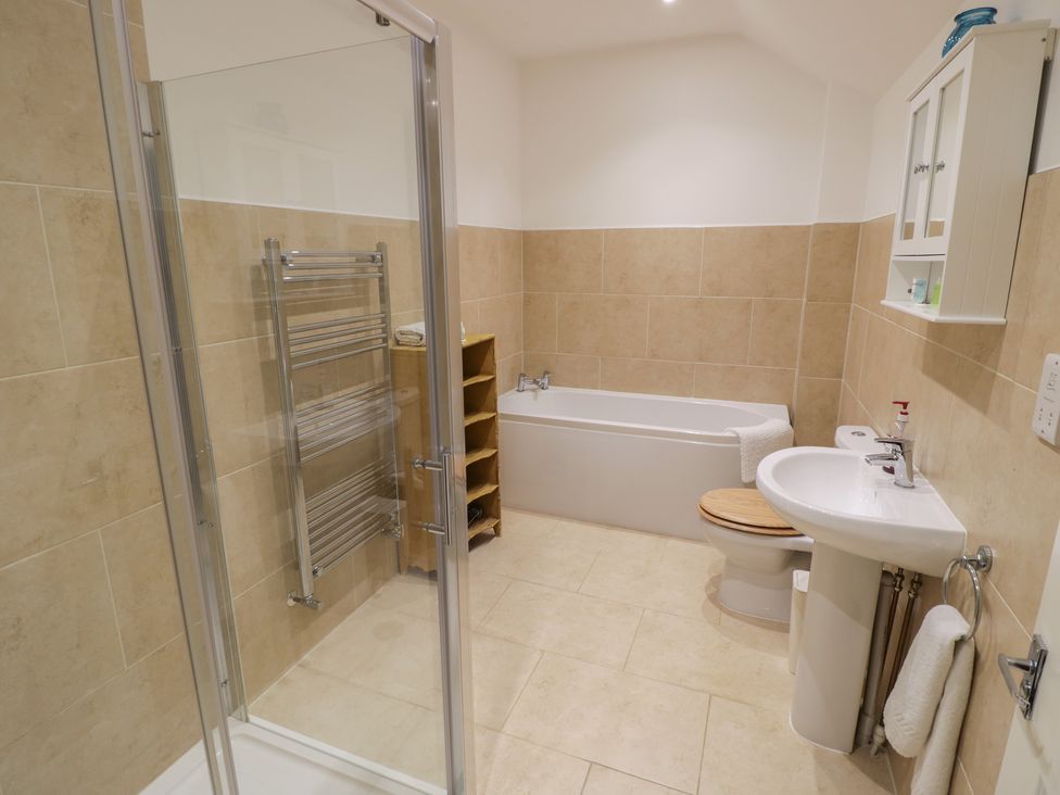 A bathroom with a bathtub, shower, sink, and towel rack at The Woods