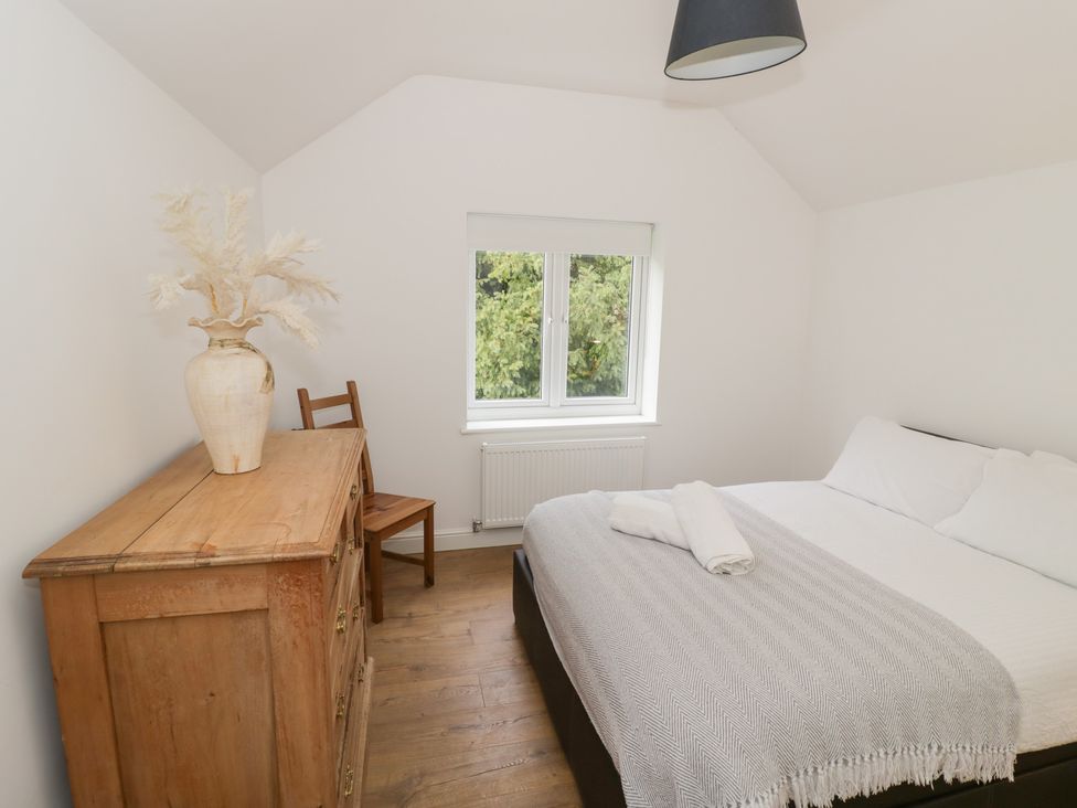 A bedroom with a bed, chair, dresser, and window at The Woods 