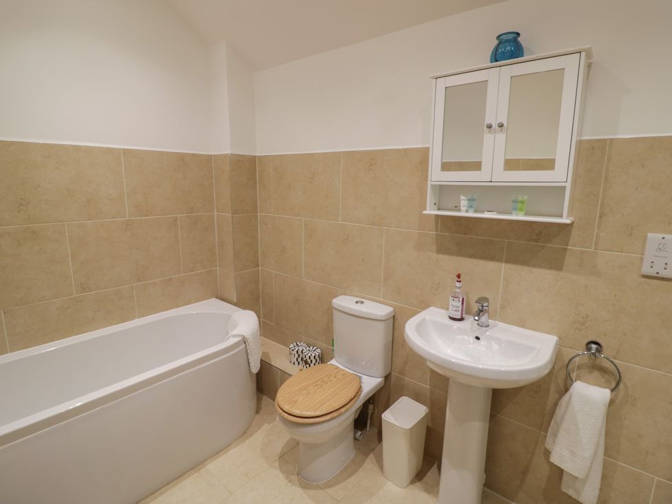 A bathroom with a tub, toilet, sink and mirror cabinet at The Woods