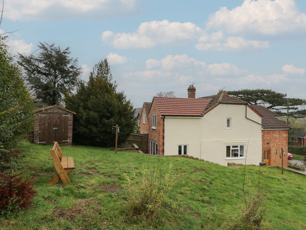 A house with a shed and bench in a yard at The Woods in 