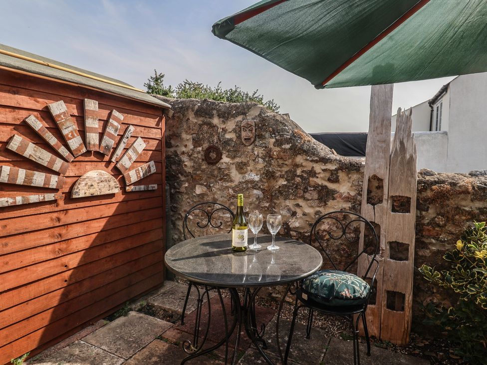 An outdoor area with a table set, wine bottle, and glasses at Garden Studio at Stanley House in Charmouth
