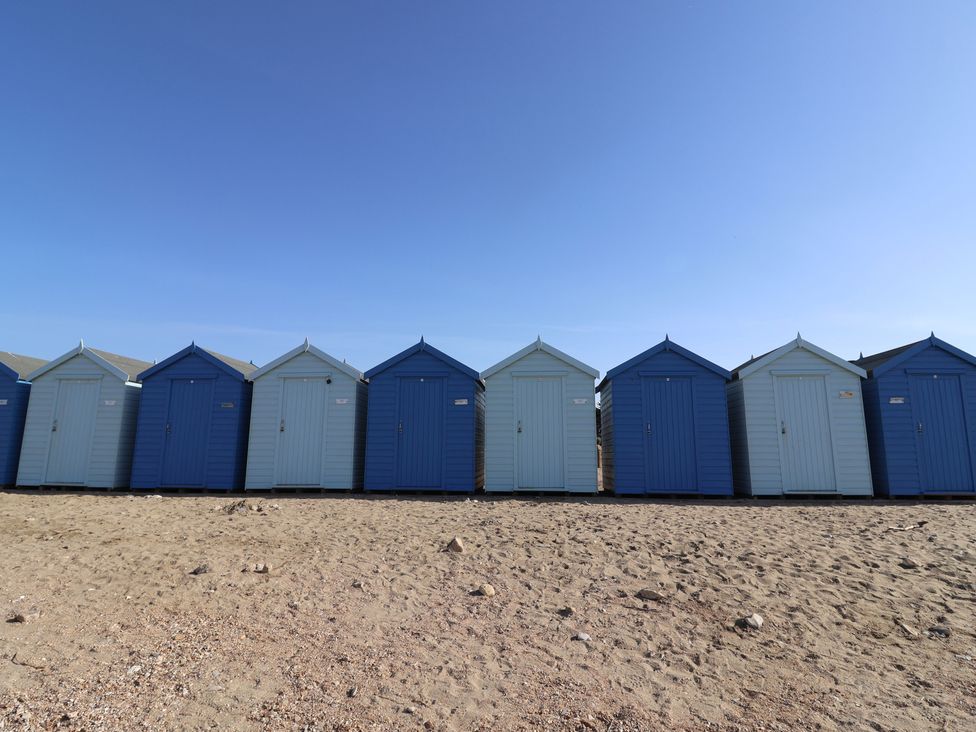 A row of blue beach huts at the beach at Garden Studio at Stanley House Charmouth
