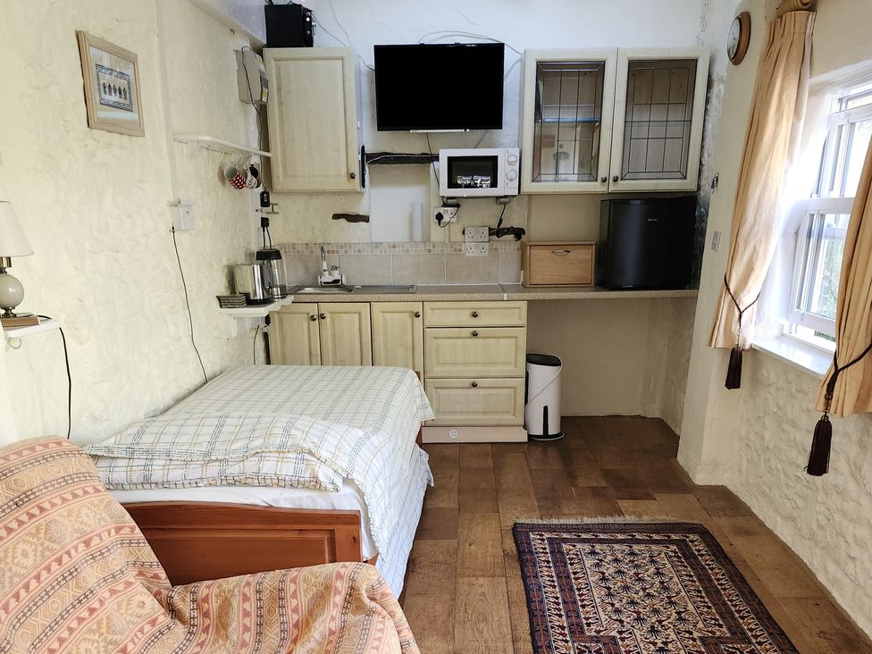A studio with bed, kitchenette and television at Garden Studio at Stanley House Charmouth
