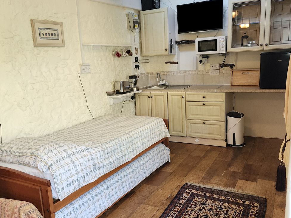 A studio with a bed and kitchen area at Garden Studio at Stanley House, Charmouth