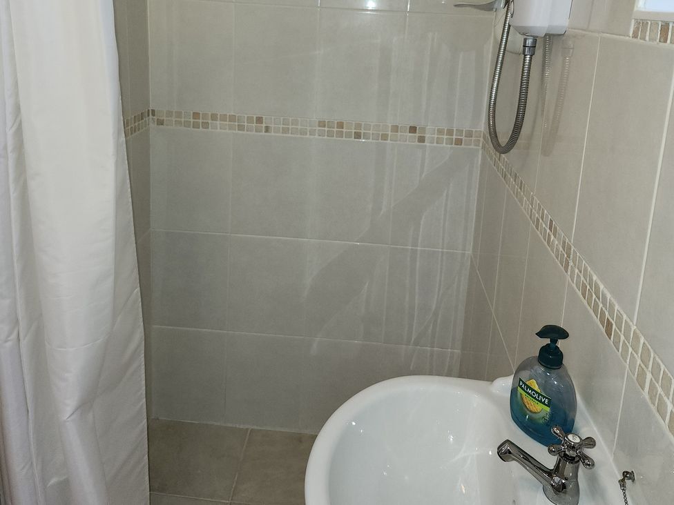 A shower area with a sink and soap dispenser at Garden Studio at Stanley House, Charmouth