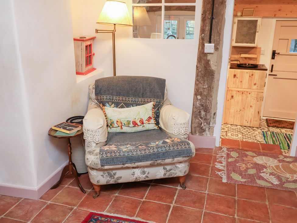 A living room with an armchair and a side table at The Hare & the Bumblebee Cottage