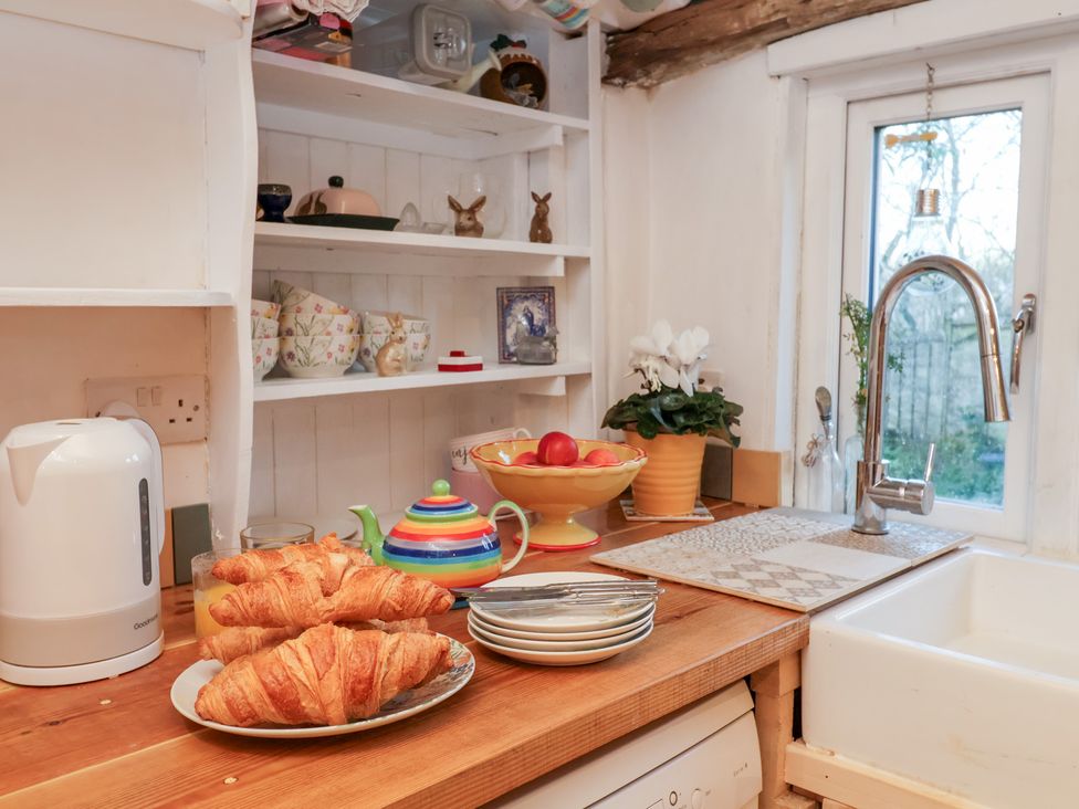 A kitchen with croissants on a plate and a fruit bowl at The Hare & the Bumblebee Cottage