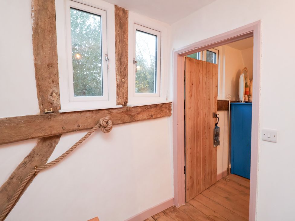 A room with windows and a wooden door at The Hare & the Bumblebee Cottage
