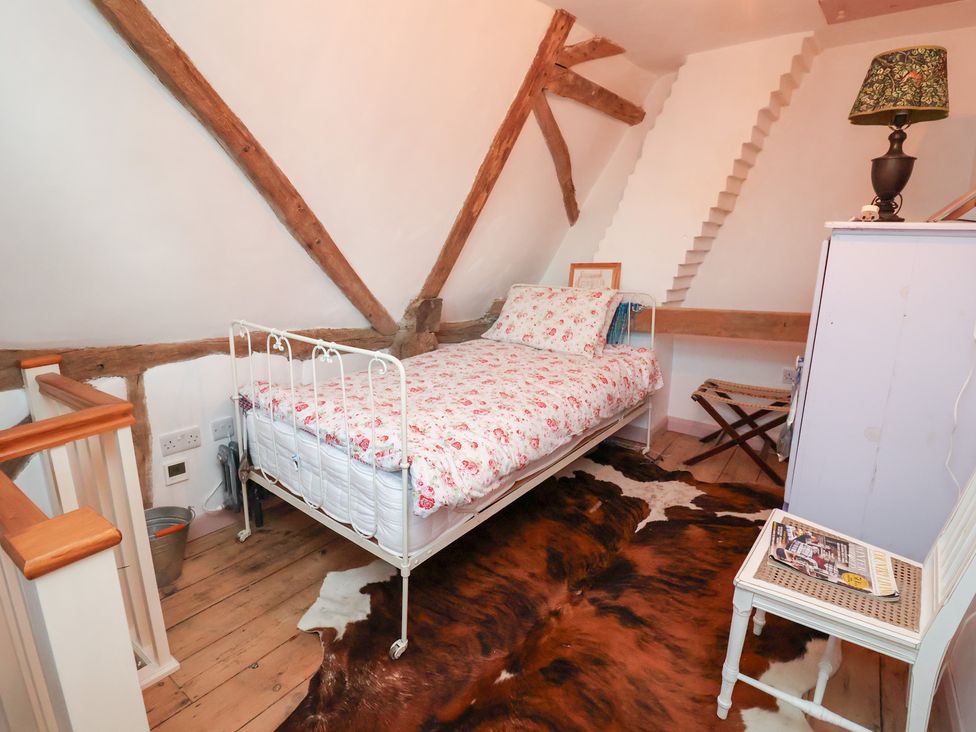 A bedroom featuring a bed with floral bedding at The Hare & the Bumblebee Cottage