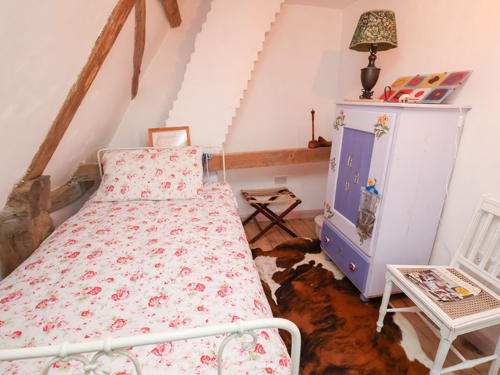 A bedroom with a bed and wardrobe at The Hare & the Bumblebee Cottage