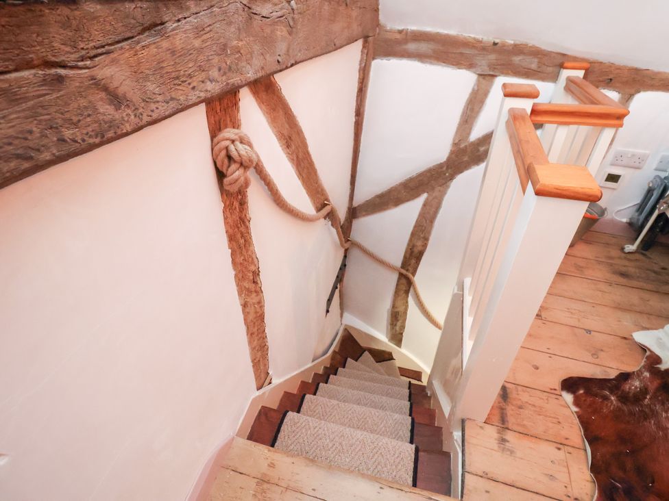 A staircase with wooden handrail and wall details at The Hare & the Bumblebee Cottage 