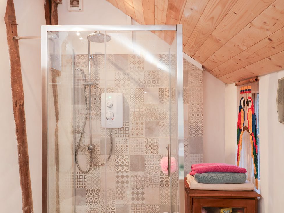 A shower area with tiles and towels at The Hare & the Bumblebee Cottage