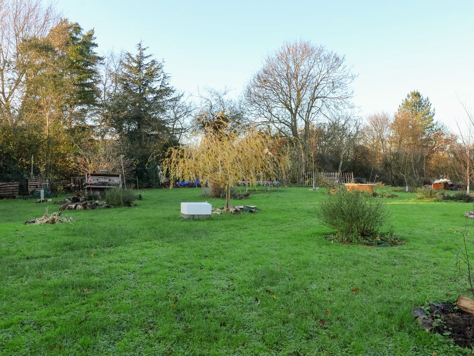 A garden with trees and grass at The Hare & the Bumblebee Cottage
