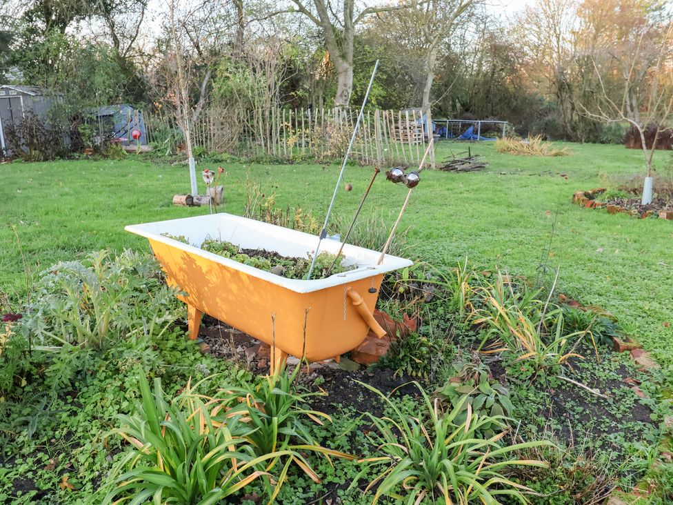 A garden with a bathtub planter and various plants at The Hare & the Bumblebee Cottage