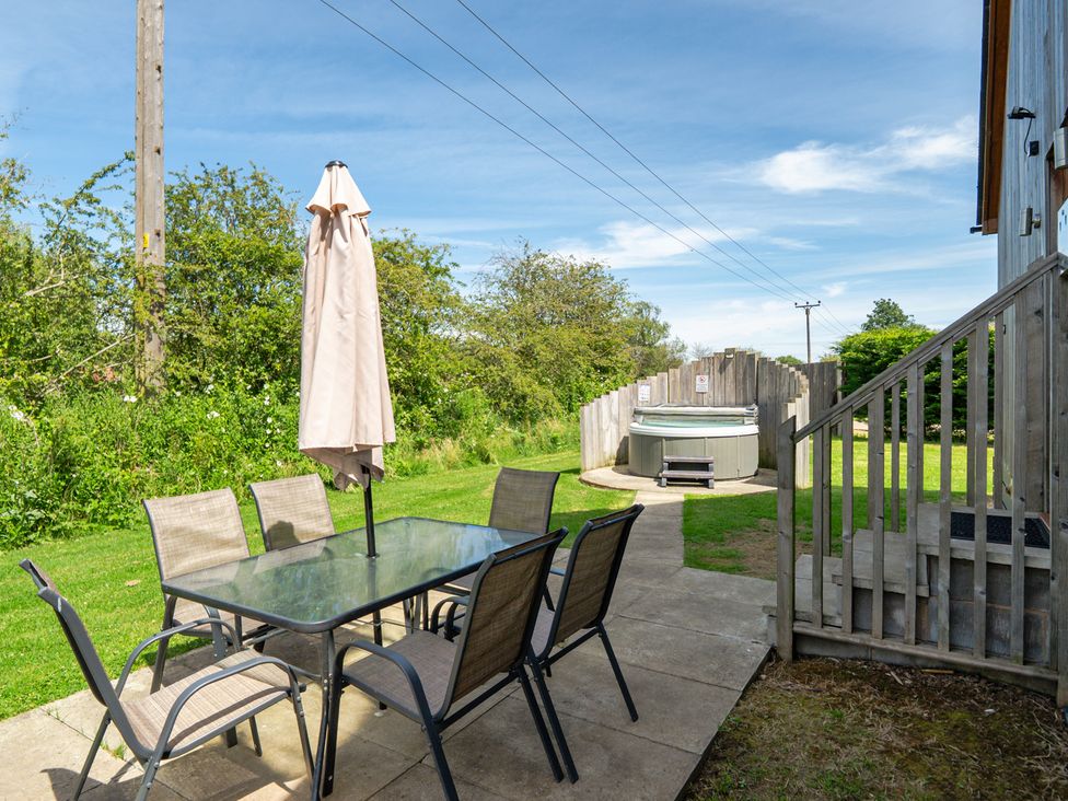 A garden with a table and chairs beside a hot tub at Aspen Lodge Near Brigg