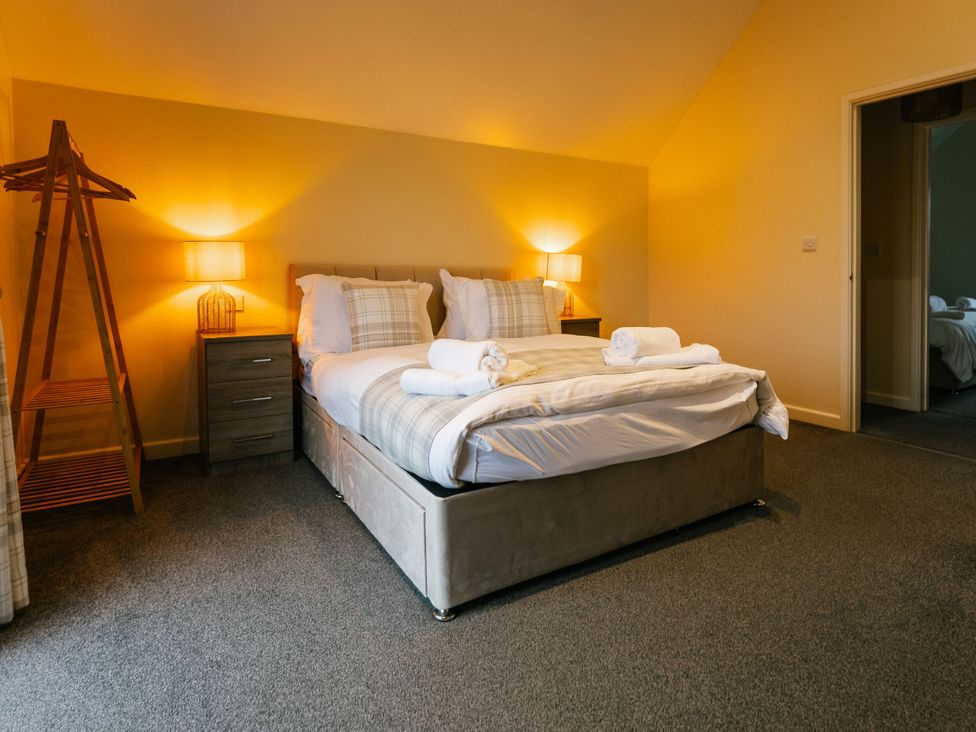 A bedroom with a bed and bedside table at Sage Lodge, Brigg