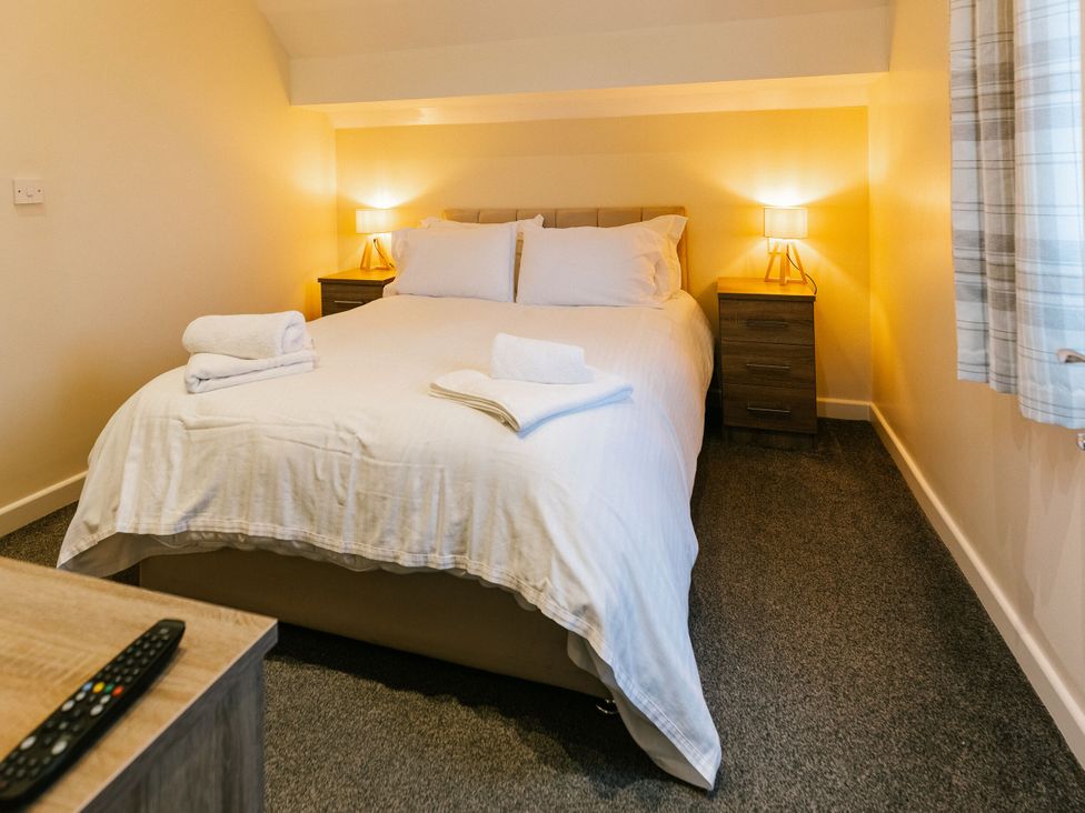 A bedroom with a bed and nightstand at Sage Lodge in Brigg