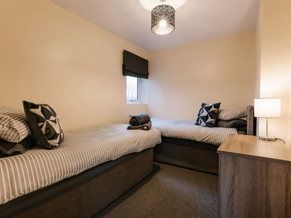 A bedroom with two single beds and a lamp at Raven Lodge in Brigg