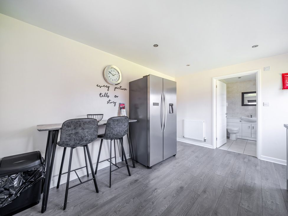 A kitchen with bar stools and refrigerator at Raven Lodge Near Brigg