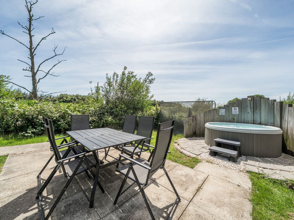 An outdoor area with a table, chairs and a hot tub at Raven Lodge Near Brigg