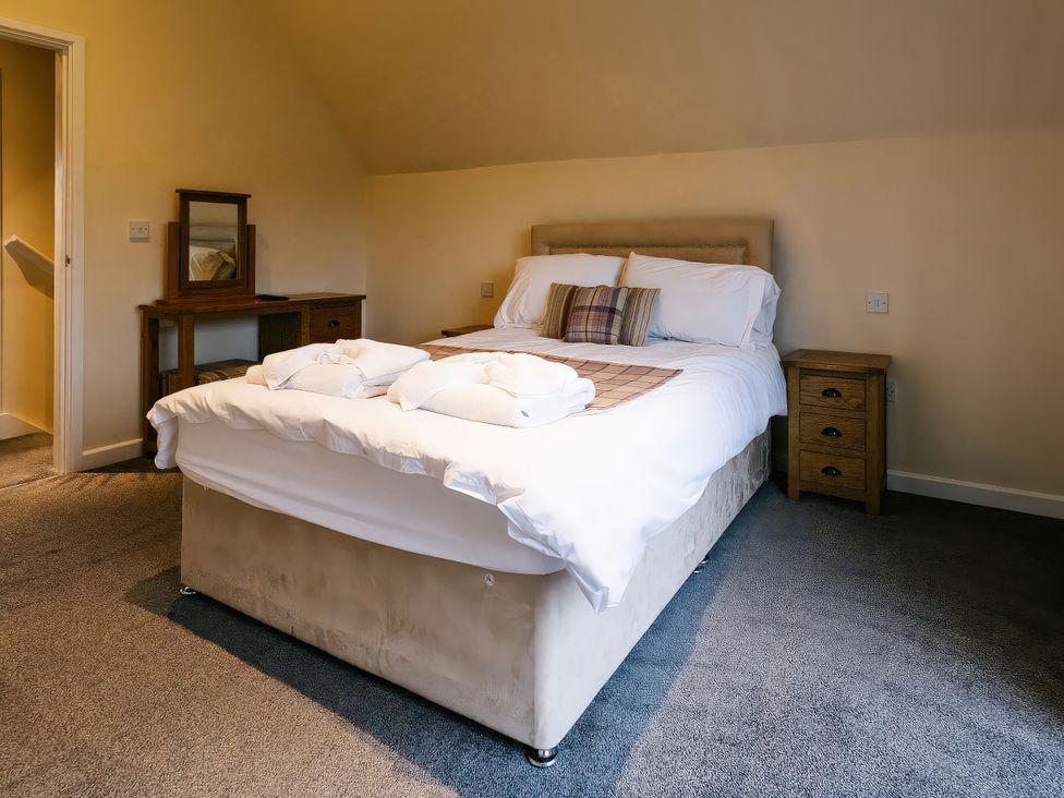A bedroom with a bed and wooden furniture at Paddington Lodge in Brigg