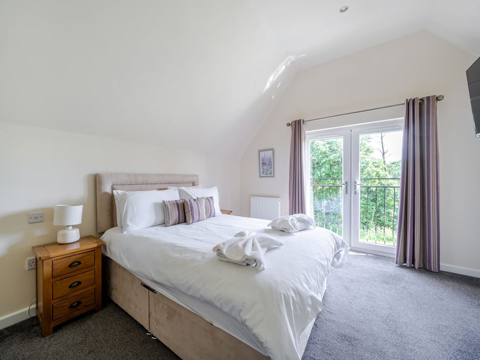 A bedroom with a bed and balcony doors at Paddington Lodge Near Brigg