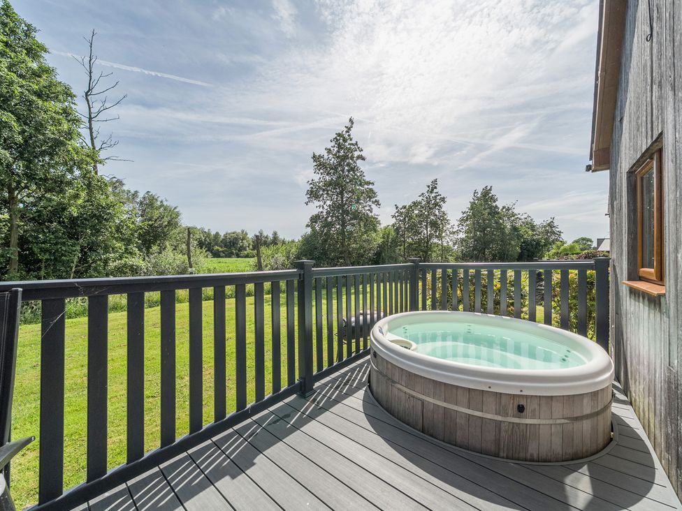 An outdoor area with a hot tub on a deck at Paddington Lodge near Brigg