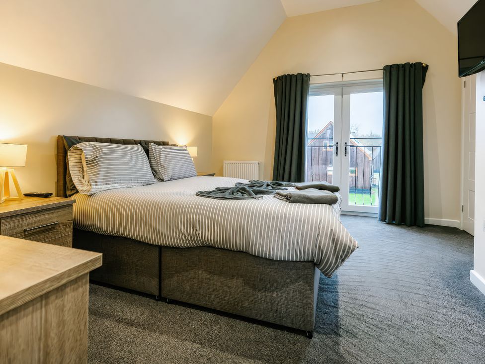 A bedroom with a bed and balcony doors at Charcoal Lodge in Brigg
