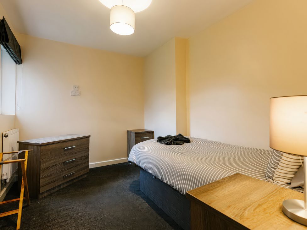 A bedroom with a bed, two drawers, and a lamp at Charcoal Lodge in Brigg