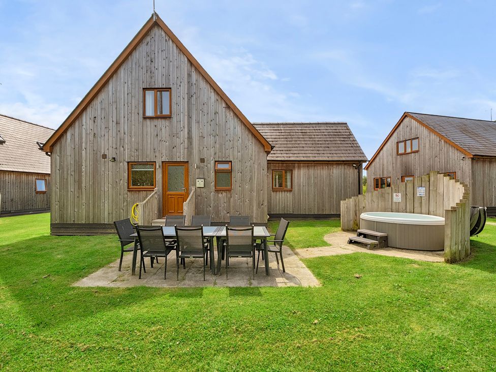 An outdoor area with wooden cabins and a hot tub at Charcoal Lodge Brigg