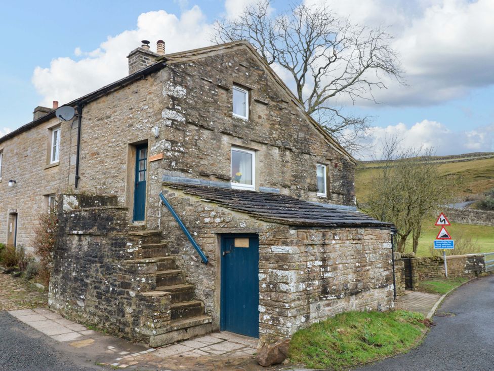 A stone house with stairs and a blue door at Wain Wath Cottage in Richmond