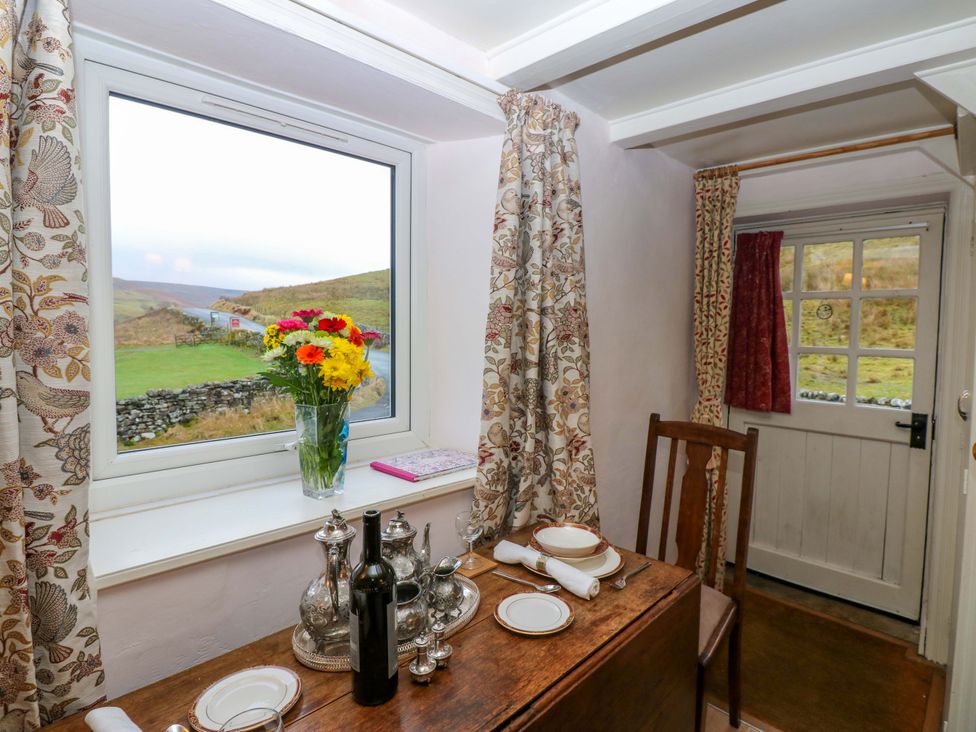 A dining room with a table set and a view outside at Wain Wath Cottage in Richmond