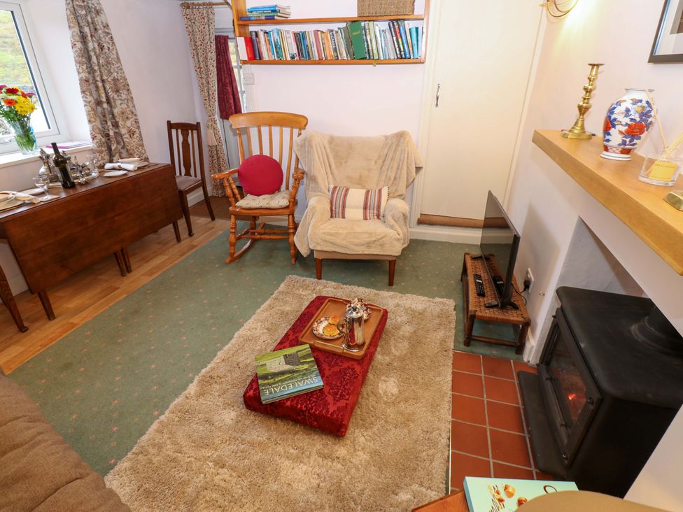 A living room with a table and bookshelves at Wain Wath Cottage Richmond