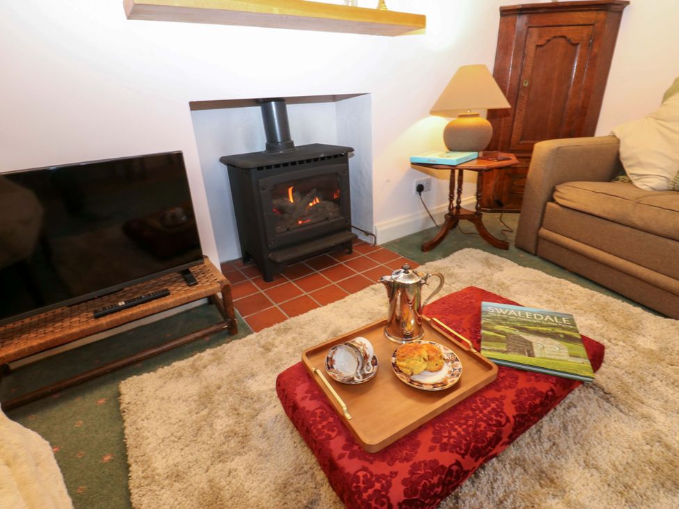 A living room with a stove and coffee table at Wain Wath Cottage in Richmond
