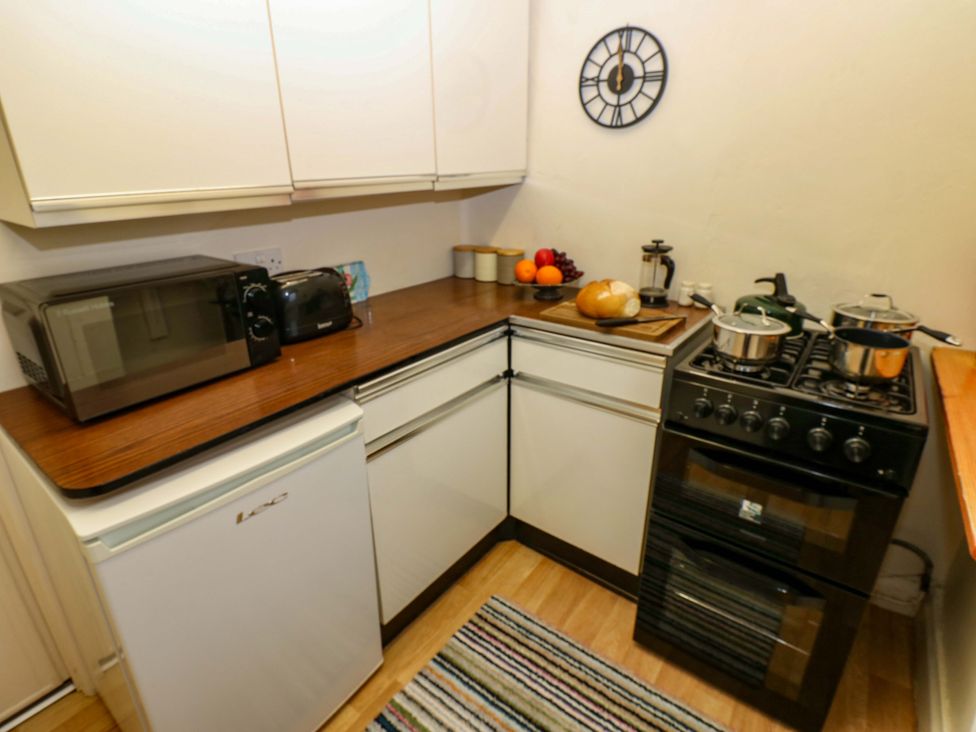 A kitchen with a stove, refrigerator, and utensils at Wain Wath Cottage in Richmond