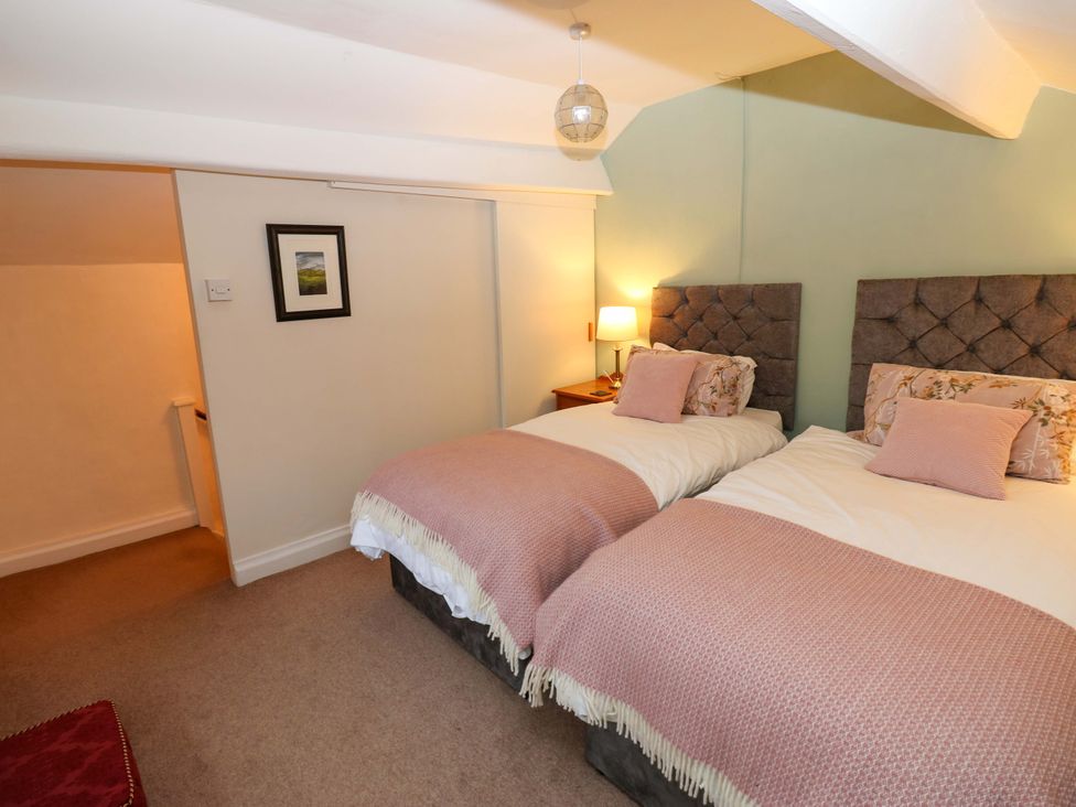 A bedroom with two beds and a bedside table at Wain Wath Cottage in Richmond