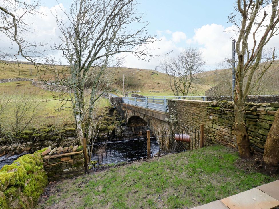 A bridge over a river with trees and grass at Wain Wath Cottage in Richmond