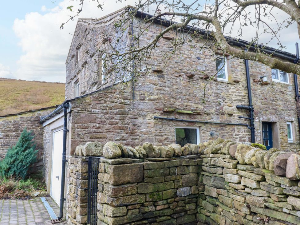 A house with stone wall and trees at Wain Wath Cottage in Richmond